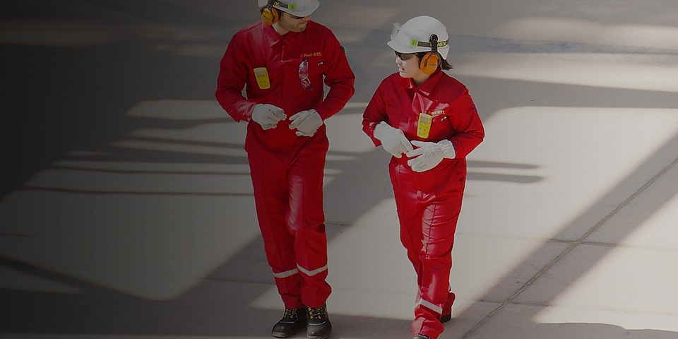 Férfi és női munkás piros overallban és fehér sisakban, fülvédővel