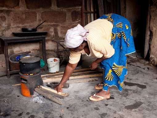 Nyílt tűzhelyen főző hölgy Nigériában
