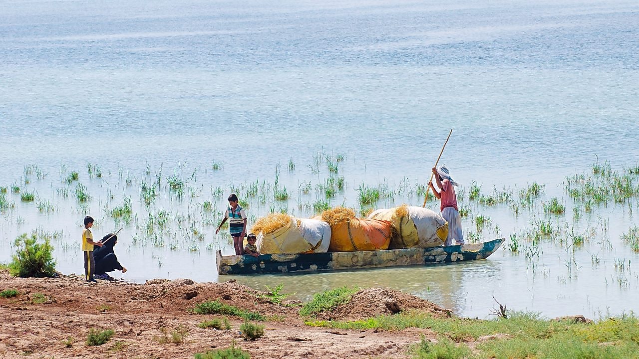 Az elöntött Hawizeh-mocsáron átkelő helyiek, az iraki Majnoon-projekt közelében