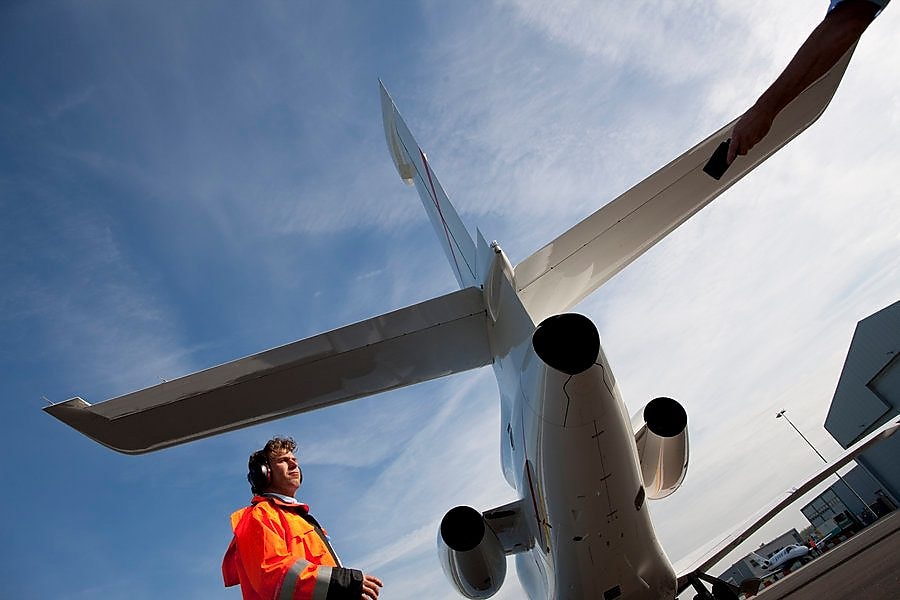Fotó a személyzet egyik tagjáról alulnézetben, amint egy repülőgép farokrésze alatt sétál