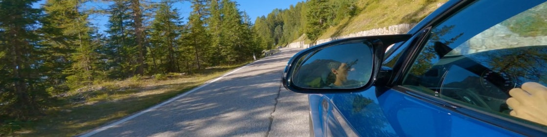 kék autó suhan fenyőfákkal övezett hegyi úton