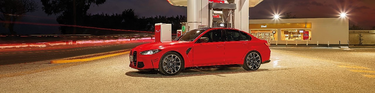 A képen bal oldalán egy mosolygó nőt látunk, a háttérben pedig egy hegyekbe tartó autópályát esti fényekben. A kép közepén pedig a Shell V-Power Diesel logo található.