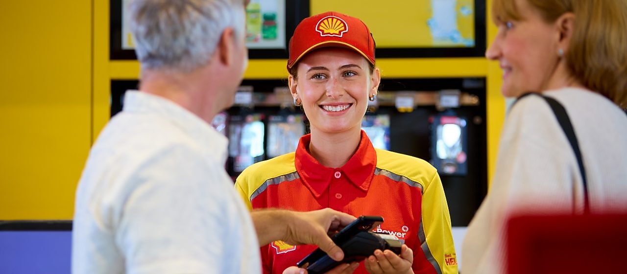 Shell alkalmazott mosolyogva fogadja a fizetést az egyik fogyasztótól