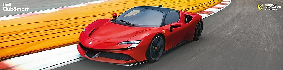 Egy versenypályán száguldó piros Ferrari roadcar látható balról jobbra tart.