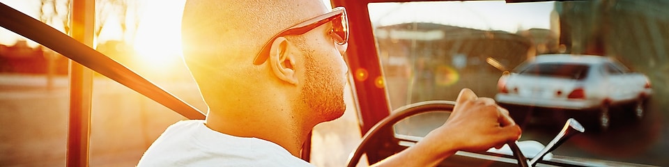 Napszemüveges férfi autót vezet.