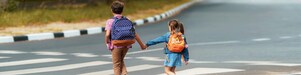 Gyerekek kézenfogva sétálnak át a gyalogátkelőhelyen