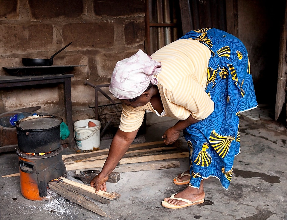 Nyílt tűzhelyen főző hölgy Nigériában